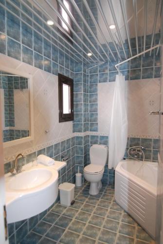 a bathroom with a sink and a toilet and a tub at Penelope Apartment Hotel in Dassia
