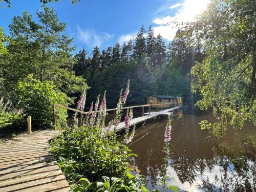 a house on a bridge over a river with flowers at Houseboat U Vodníka in Krásná Hora