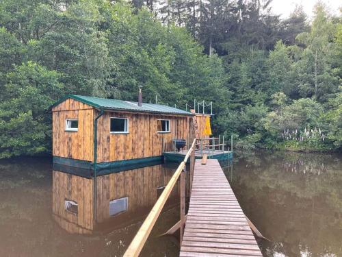 a wooden house on a dock on a body of water at Houseboat U Vodníka in Krásná Hora