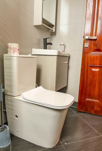 a bathroom with a white toilet and a sink at iKHAYA RESIDENCES MUNYONYO in Kampala