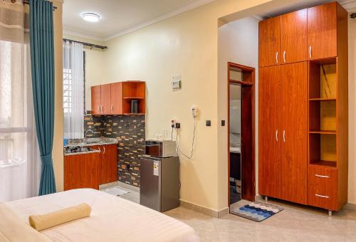 a kitchen with wooden cabinets and a refrigerator in a room at iKHAYA RESIDENCES MUNYONYO in Kampala
