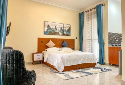 a bedroom with a large bed and a chair at iKHAYA RESIDENCES MUNYONYO in Kampala