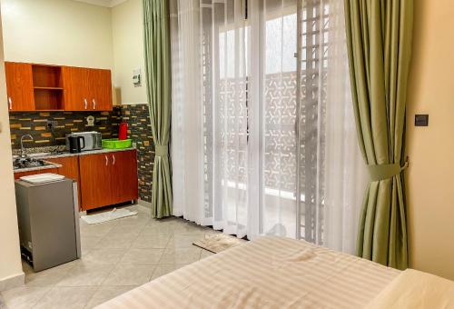 a kitchen with a bed and a large window at iKHAYA RESIDENCES MUNYONYO in Kampala