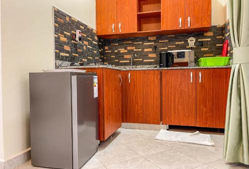 a kitchen with wooden cabinets and a stainless steel refrigerator at iKHAYA RESIDENCES MUNYONYO in Kampala