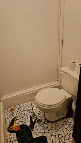 a bathroom with a toilet and a butterfly tile floor at Cuarto Sol - Casa Oropopo in Cocles