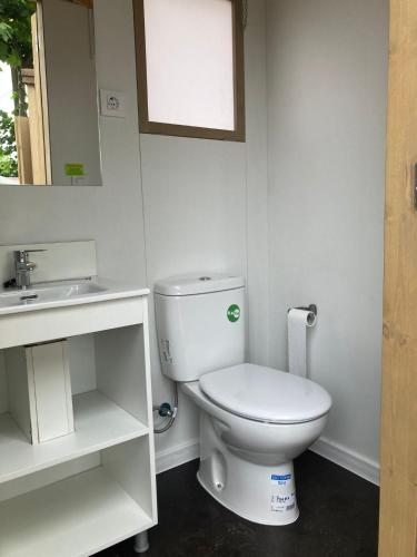 a white bathroom with a toilet and a sink at Camping Paxariñas in Portonovo