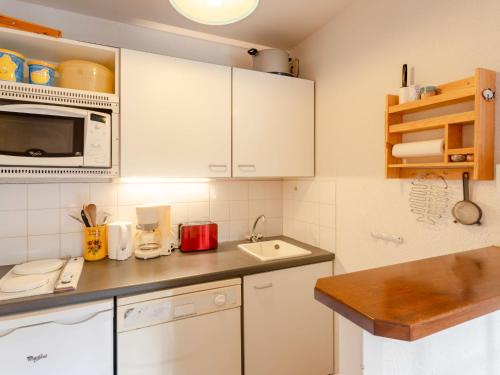 une cuisine avec des armoires blanches, un évier et un micro-ondes dans l'établissement Apartment Les Jardins de la Côte Fleurie by Interhome, à Villers-sur-Mer