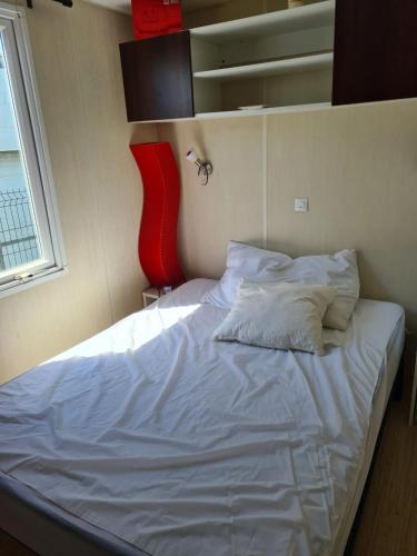 un lit blanc dans une chambre avec une fenêtre dans l'établissement Bungalow charmant à Sigean avec piscine et jardin clôturé, à Sigean