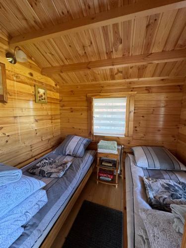 a log cabin with two beds and a window at Domek przy Róży in Ostromice