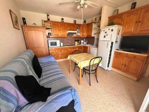 Il comprend une cuisine équipée d'un canapé, d'une table et d'un réfrigérateur. dans l'établissement Appartement Port Royal, au Grau-du-Roi