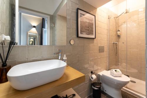 a bathroom with a tub and a toilet and a sink at BmyGuest - The Marquis Luxury Garden Apartment in Porto
