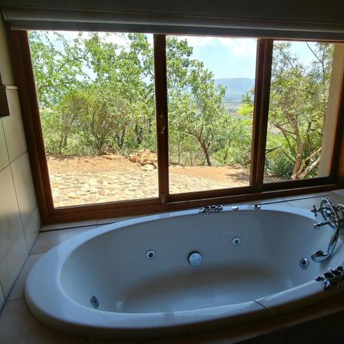 a bath tub in a bathroom with a window at Sky Lodge in Hartbeespoort