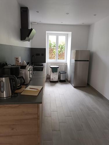 d'une cuisine avec un comptoir, un réfrigérateur et une fenêtre. dans l'établissement Maison centre de sainte mère église, à Sainte-Mère-Église
