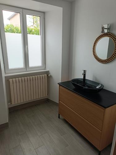 La salle de bains est pourvue d'un lavabo et d'un miroir sur une commode. dans l'établissement Maison centre de sainte mère église, à Sainte-Mère-Église