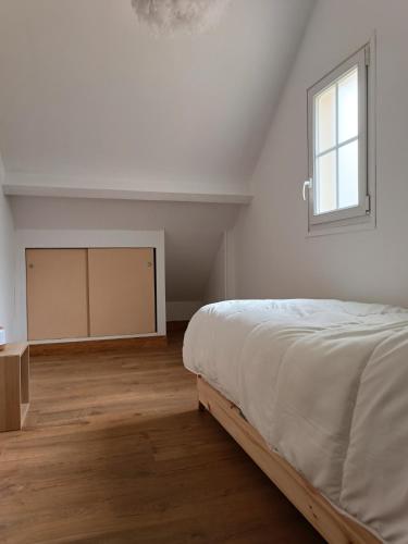 a white bedroom with a bed and a window at la parenthèse in Sainte-Mère-Église