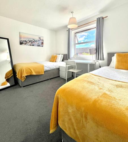 a hotel room with two beds and a window at Central MK Home, Garden and Free Private Driveway Parking! 4 Beds Fully Equipped Train station 5 Mins in Milton Keynes
