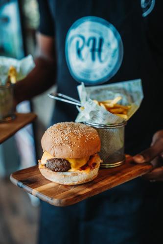 a person holding a hamburger and a cup of fries at Hotel RH Boutique Aruba in Oranjestad