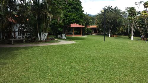 a park with green grass and trees and a building at Hotel Cibeles Resort in Heredia