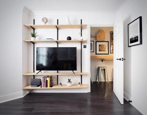 a living room with a flat screen tv on a shelf at Spacious Two Bedroom Apartment in the Heart of Notting Hill in London