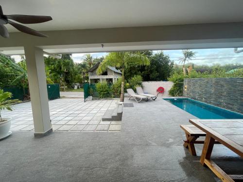 a patio with a swimming pool with a table and a table at Maison Marie-Jeanne in Anse Possession