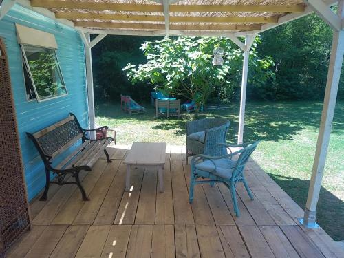 une terrasse couverte avec deux bancs et une table. dans l'établissement Mobile home style créole, à Graveson
