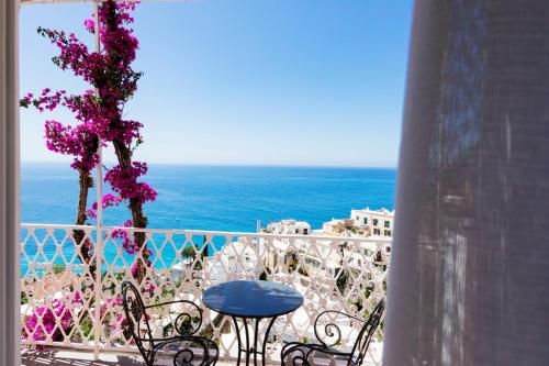 a balcony with chairs and a tree with purple flowers at La Bizantina Luxury Villa in Positano