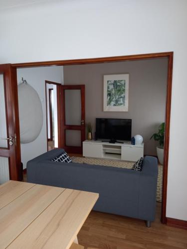 a living room with a blue couch and a tv at Buddies Charm Apt - Self Catering in Aveiro