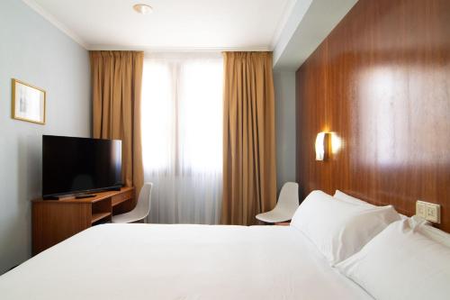a hotel room with a bed and a flat screen tv at Hotel Beratxa in Tafalla