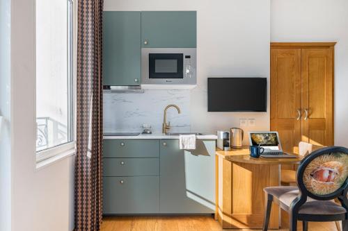 a kitchen with blue cabinets and a desk with a laptop at Villa Elisa M in Aubenas