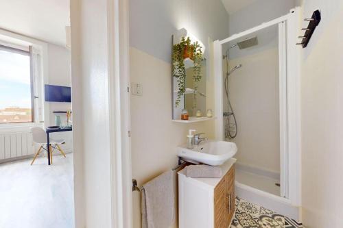 ein weißes Badezimmer mit Waschbecken und Dusche in der Unterkunft Le Cocon dans les Nuages in Villeurbanne