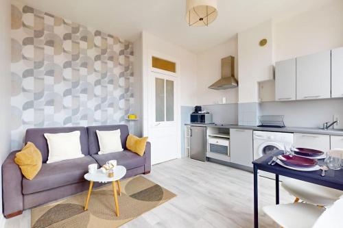 Il comprend un salon avec un canapé violet et une cuisine. dans l'établissement Le Cocon dans les Nuages, à Villeurbanne