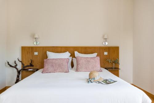 a white bed with two pillows and a hat on it at Villa Elisa M in Aubenas