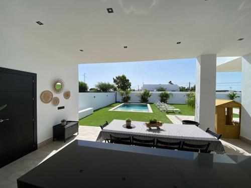 a living room with a table and a pool at Villa con piscina Camino Doñana in Sanlúcar de Barrameda
