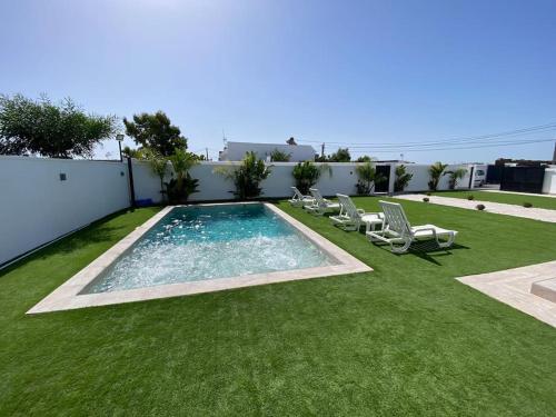 a swimming pool with lounge chairs on a lawn at Villa con piscina Camino Doñana in Sanlúcar de Barrameda
