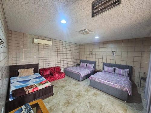 two beds and a couch in a room at ghroob farmhouse villa in Al Ḩamrānīyah
