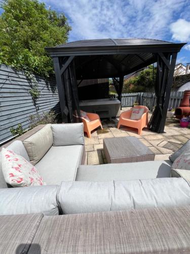 a patio with a couch and chairs under a gazebo at Portaferry Waterfront Townhouse with Hot Tub in Portaferry