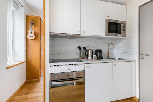 a white kitchen with a stove and a microwave at Villa Elisa M in Aubenas