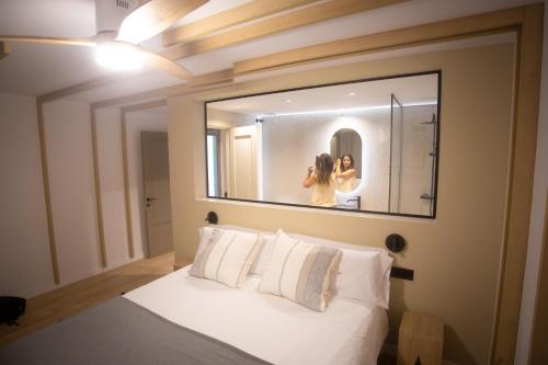 a woman taking a picture in a mirror over a bed at L'indret del Pedraforca Adults Only in Saldés