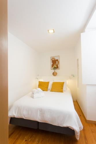 a bedroom with a white bed with yellow pillows at Casas da Comedia in Coimbra
