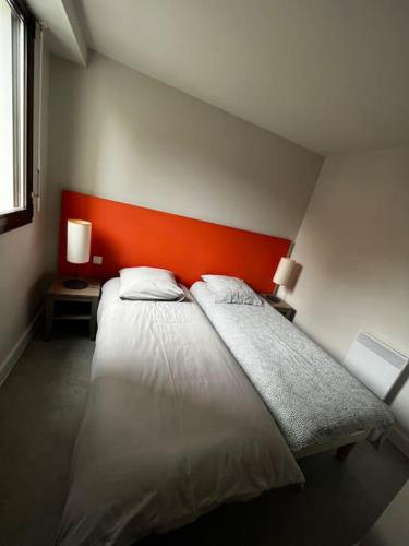 - une chambre avec un lit blanc et une tête de lit orange dans l'établissement Appartement accès plage, à Perros-Guirec