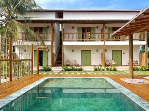 a villa with a swimming pool in front of a house at Jardim Cumuru - Suítes in Cumuruxatiba