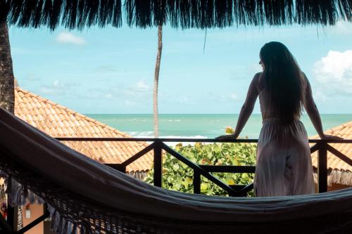 a woman standing on a balcony looking out at the ocean at Pousada Tabapitanga in Porto De Galinhas