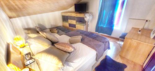 une chambre avec un grand lit avec des oreillers dessus dans l'établissement Au 26BIS, 2 Appartements MONTREUX, 1 Apartment niveau 0 et un autre appartement duplex niveau 1 et 2, 15 minutes à pieds du centre de Montreux, Lac Léman, idéal pour balades en ville, Montagne, festivals, Casino, plages, ski, Fredy Mercury, Marché de Noël, à Montreux