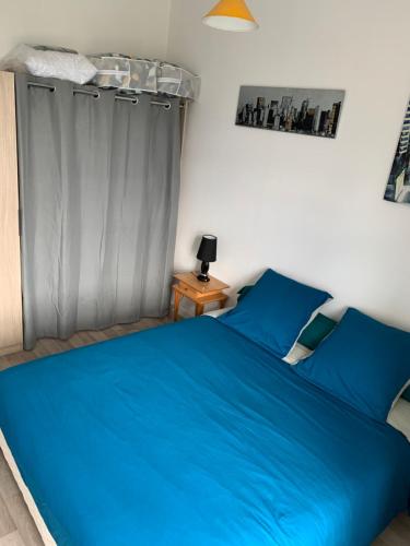 - une chambre avec un lit bleu et un rideau dans l'établissement Appartement 120m2, à Aleçon