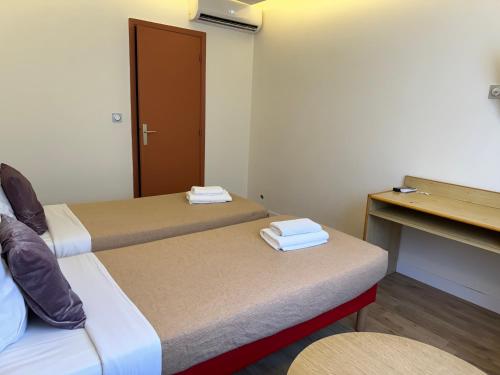 a hotel room with two beds and a desk at Hotel Panorama in Grasse