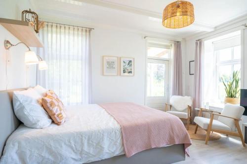 a bedroom with a bed and a desk and windows at Thuis in Sauwerd in Sauwerd