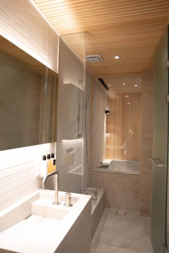a bathroom with a sink and a shower and a mirror at B'amu Hotel in Busan
