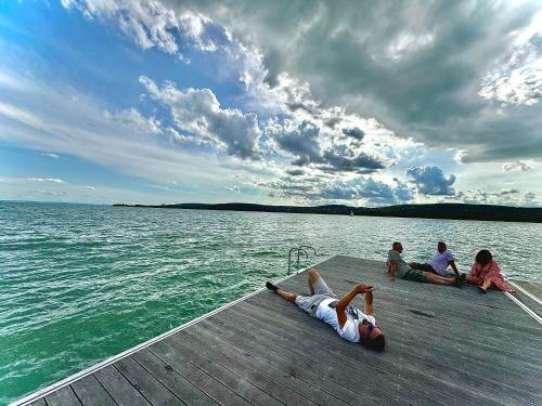 a group of people sitting on a dock on the water at Willow Nest in Balatonfůzfő