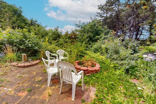 four white chairs and a table in a garden at Bayview in Truro
