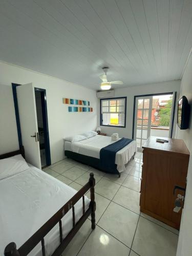 a bedroom with two beds and a large window at Brothers Suites Centro Búzios in Búzios